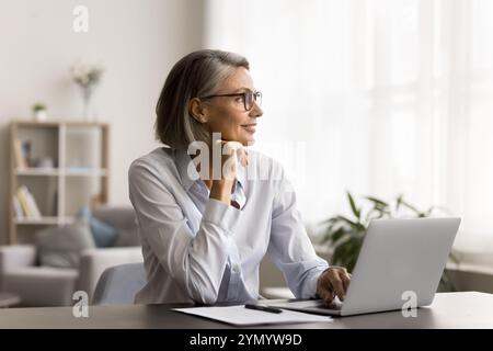 Donna libera e felice da sogno con eleganti occhiali da vista che lavorano a casa Foto Stock