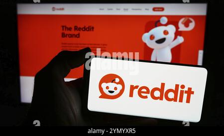 Stuttgart, Germania, 03-15-2024: Persona con smartphone con logo della società statunitense di social media Reddit Inc. Davanti al sito web. Mettere a fuoco il display del telefono Foto Stock