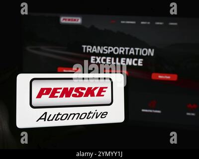 Stoccarda, Germania, 05-23-2024: Persona che possiede uno smartphone con il logo della concessionaria statunitense Penske Automotive Group Inc. Davanti al sito Web. Messa a fuoco o Foto Stock