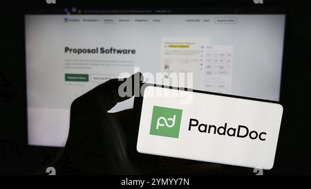 Stoccarda, Germania, 05-16-2024: Persona che possiede uno smartphone con il logo della società statunitense PandaDoc Inc. Di fronte al sito web. Focu Foto Stock