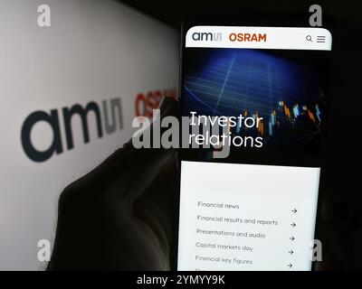 Stoccarda, Germania, 05-31-2024: Persona che detiene uno smartphone con sito web della società austriaca di elettronica ams OSRAM AG davanti al logo. Concentrati sul centro Foto Stock