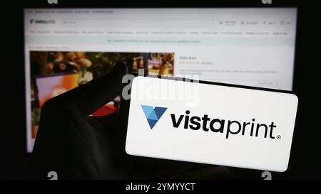 Stoccarda, Germania, 04-12-2024: Persona con smartphone con logo della società di personalizzazione di massa Vistaprint (Vista) davanti al sito web. Concentrati sul pho Foto Stock
