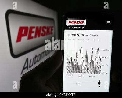 Stoccarda, Germania, 05-23-2024: Persona che detiene il cellulare con il sito web della concessionaria statunitense Penske Automotive Group Inc. Davanti al logo. Concentrati su Foto Stock