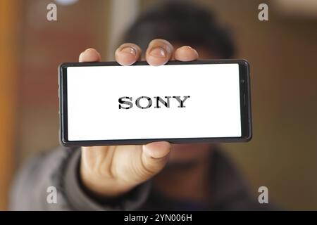 SONY è una società giapponese. SONY è un'azienda produttrice di console di videogiochi e di videogiochi. Smartphone con logo SONY sullo schermo circondato da gamepad. Foto Stock