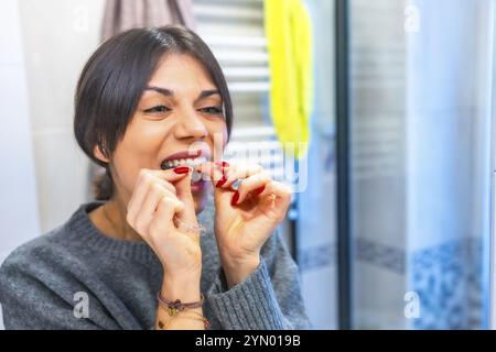 Donna che indossa un moderno allineatore dentale trasparente in bagno Foto Stock