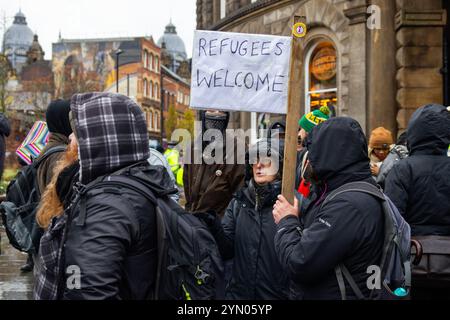 Leeds, Regno Unito. 23 NOVEMBRE 2024. Il dimostratore tiene il cartello "Refugees welcome" (accoglienza rifugiati) mentre due gruppi di protesta rivali si sono riuniti fuori Leeds Corn Exchange nelle avverse condizioni meteorologiche causate dalla tempesta Bert. I manifestanti di destra, ritenuti affiliati con i manifestanti Hull Patriots / Hull Patriotic, e altre organizzazioni di destra tennero una dimostrazione di "fermare le barche" con circa 25 partecipanti, una contro-protesta fu organizzata dal gruppo di attivisti di sinistra SUTR (Stand Up to Racism) che si riunì a breve distanza, la polizia tenne le due parti separate sotto la pioggia. Crediti: Milo Chandler/al Foto Stock