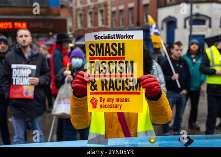 Leeds, Regno Unito. 23 NOVEMBRE 2024. Il manifestante tiene il cartello "Smash Fascism and Racism", mentre due gruppi rivali di protesta si sono riuniti fuori Leeds Corn Exchange nelle avverse condizioni meteorologiche causate da Storm Bert. I manifestanti di destra, ritenuti affiliati con i manifestanti Hull Patriots / Hull Patriotic, e altre organizzazioni di destra tennero una dimostrazione di "fermare le barche" con circa 25 partecipanti, una contro-protesta fu organizzata dal gruppo di attivisti di sinistra SUTR (Stand Up to Racism) che si riunì a breve distanza, la polizia tenne le due parti separate sotto la pioggia. Credito: Milo Cha Foto Stock