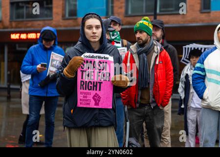 Leeds, Regno Unito. 23 NOVEMBRE 2024. Il dimostratore tiene il cartello "Smash the far right", mentre due gruppi di protesta rivali si sono riuniti fuori Leeds Corn Exchange nelle avverse condizioni meteorologiche causate da Storm Bert. I manifestanti di destra, ritenuti affiliati con i manifestanti Hull Patriots / Hull Patriotic, e altre organizzazioni di destra tennero una dimostrazione di "fermare le barche" con circa 25 partecipanti, una contro-protesta fu organizzata dal gruppo di attivisti di sinistra SUTR (Stand Up to Racism) che si riunì a breve distanza, la polizia tenne le due parti separate sotto la pioggia. Credito: Milo Chandler Foto Stock