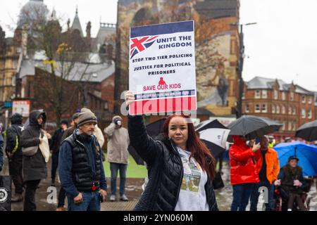 Leeds, Regno Unito. 23 NOVEMBRE 2024. lady regge il cartello "Unite the Kingdom, stop two Tier Policing" mentre due gruppi di protesta rivali si sono riuniti fuori Leeds Corn Exchange nelle avverse condizioni meteorologiche causate da Storm Bert. I manifestanti di destra, ritenuti affiliati con i manifestanti Hull Patriots / Hull Patriotic, e altre organizzazioni di destra tennero una dimostrazione di "fermare le barche" con circa 25 partecipanti, una contro-protesta fu organizzata dal gruppo di attivisti di sinistra SUTR (Stand Up to Racism) che si riunì a breve distanza, la polizia tenne le due parti separate sotto la pioggia. Credito: Foto Stock