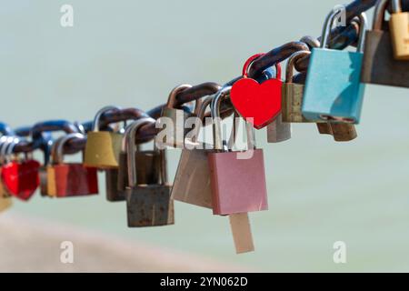 Lucchetti rossi a forma di cuore e altri lucchetti su una catena blu Foto Stock