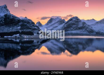Cielo colorato al tramonto sulle montagne innevate che si riflettono nell'acqua Foto Stock