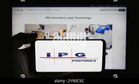 Stoccarda, Germania, 07-06-2024: Persona che detiene il cellulare con il logo della società statunitense di laser IPG Photonics Corporation davanti alla pagina web aziendale. Messa a fuoco o Foto Stock
