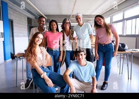 Ritratto di un felice gruppo multirazziale di studenti che posa insieme in classe con un insegnante dai capelli grigi. Foto Stock