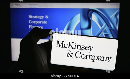 Stuttgart, Germania, 03-16-2024: Persona che detiene un telefono cellulare con il logo della società di consulenza americana McKinsey and Company davanti alla pagina web. Concentrati Foto Stock