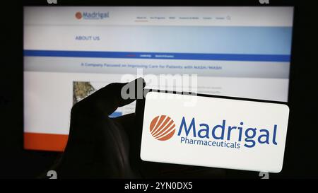 Stoccarda, Germania, 06-26-2024: Persona con smartphone con logo della società biofarmaceutica Madrigal Pharmaceuticals Inc. Davanti al sito web. Fil Foto Stock