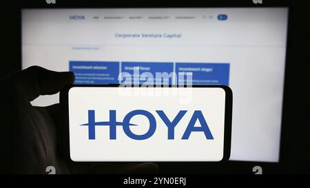 Stoccarda, Germania, 07-19-2024: Persona che detiene il cellulare con il logo della società giapponese di strumenti di precisione Hoya Corporation davanti alla pagina web. FOC Foto Stock