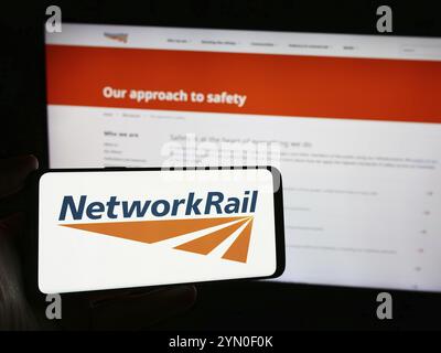 Stoccarda, Germania, 03-27-2024: Persona in possesso di smartphone con logo della società di infrastrutture ferroviarie Network Rail Limited davanti al sito web. Concentrati Foto Stock