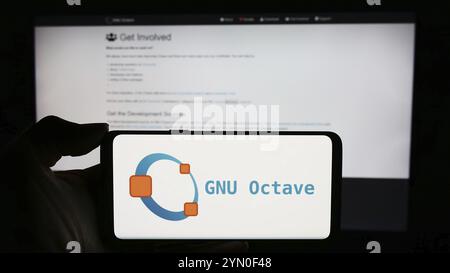 Stoccarda, Germania, 03-13-2024: Persona che tiene un cellulare con il logo del linguaggio di programmazione scientifica GNU Octave davanti alla pagina web. Concentrati sul telefono d Foto Stock