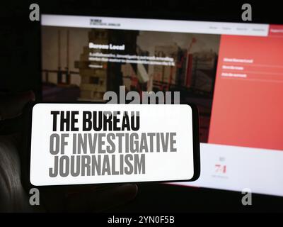 Stoccarda, Germania, 04-13-2024: Persona che detiene un telefono cellulare con il logo dell'organizzazione il Bureau of Investigative Journalism (TBIJ) di fronte alla web pa Foto Stock