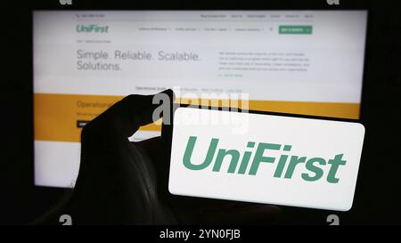 Stoccarda, Germania, 07-06-2024: Persona con smartphone con logo della società statunitense di abbigliamento protettivo UniFirst Corporation davanti al sito web. Concentrati Foto Stock