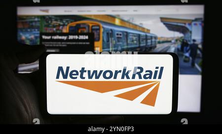 Stoccarda, Germania, 03-27-2024: Persona che detiene un cellulare con il logo della società di infrastrutture ferroviarie Network Rail Limited di fronte alla pagina web aziendale Foto Stock