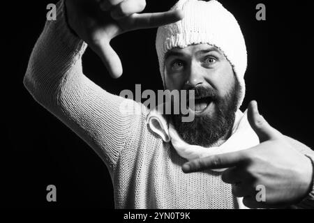 Sorridente barba che incornicia il viso con le mani. Uomo felice che crea cornice con le dita. Foto di selfie immaginarie. Il bel ragazzo in abbigliamento casual crea l'inquadratura della fotocamera Foto Stock