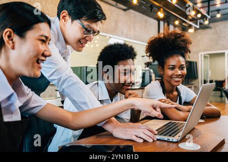 Il giovane proprietario di un bar e il team aziendale lavorano insieme per il brainstorming dei progetti utilizzando un notebook Foto Stock