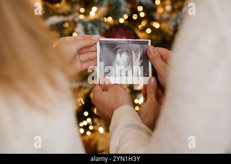 Aspettarsi la gioia: Un momento di cuore di una coppia con un'immagine a ultrasuoni in mezzo a festività. Foto Stock