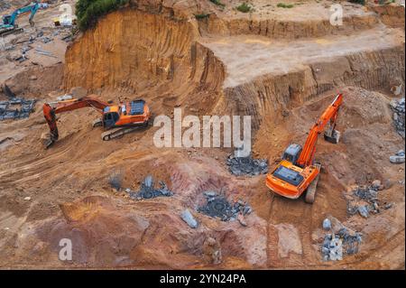 Gli escavatori scavano terreno nella fossa di fondazione di un edificio in un cantiere. Vista dall'alto Foto Stock