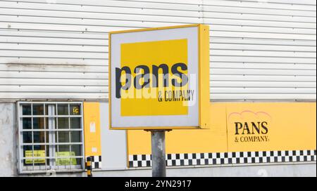 Primo piano di una pentola e di un cartello dell'azienda, che mostra il logo del marchio e la presenza sull'esterno di un edificio Foto Stock