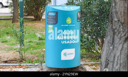 Contenitore blu per la raccolta dell'olio da cucina usato in un parco pubblico, promuovendo il riciclaggio e la consapevolezza ambientale Foto Stock