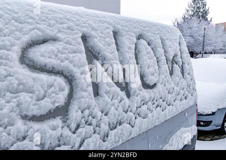 L'attacco dell'inverno, la prima nevicata, la parola neve scritta sul corpo dell'auto nella neve Foto Stock