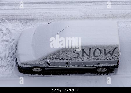 Piccola valigia coperta di neve durante l'inverno nel parcheggio Foto Stock