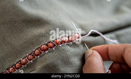 Cucitura per cucitura: La mano di una donna crea con ago e filo Foto Stock