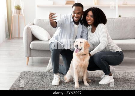 Giovane coppia nera che prende selfie con il cane a casa Foto Stock