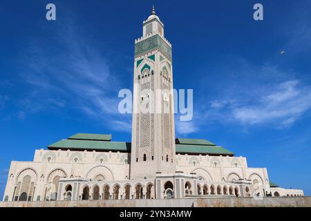 Moschea di Hassan II, Casablanca, Marocco, il secondo minareto più alto del mondo, alto 210 metri, mostrato in posizione centrale, contro un cielo blu con nuvole bianche Foto Stock