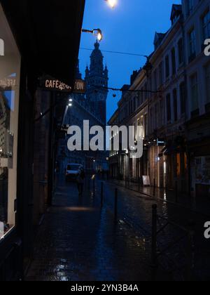 Scopri le luci in una notte di pioggia su Rue Lepelletier, Lille, con la torre dell'orologio del Palais De la Bourse Foto Stock