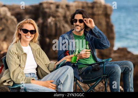 Gli amici potranno gustare bevande rinfrescanti mentre si rilassano sulle rocce in riva al mare Foto Stock