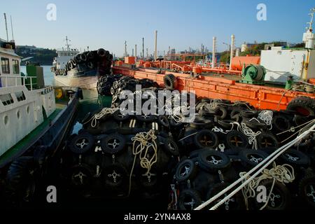 Ulsan, Corea del Sud - 14 novembre 2024: Una vista ravvicinata di barche e parafanghi marini impilati al porto di Jangsaengpo, circondato da navi industriali e chi Foto Stock