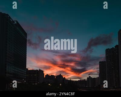 Suggestivo tramonto urbano con il vibrante cielo Rosso e Blu sopra alti edifici, che mostrano la bellezza dello skyline della città al crepuscolo Foto Stock