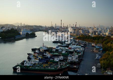 Ulsan, Corea del Sud - 14 novembre 2024: Una serena vista al crepuscolo del porto di Jangsaengpo con file di navi ormeggiate e il vasto complesso industriale di Yongyeon Foto Stock