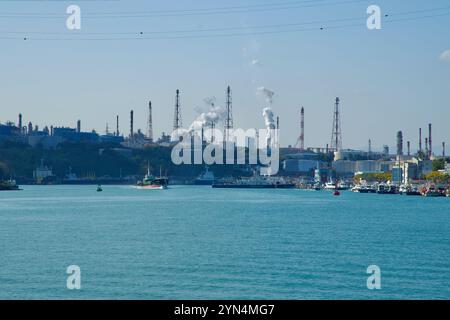 Ulsan, Corea del Sud - 14 novembre 2024: Una vista del porto di Jangseongpo con navi che navigano in acque calme e il complesso industriale Ulsan Yongyeon emitt Foto Stock