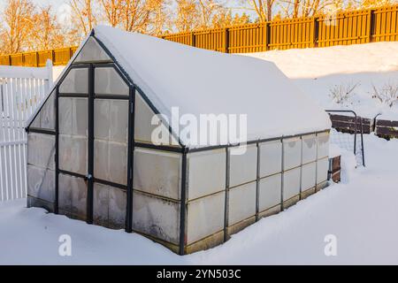 Serra coperta di neve nel cortile posteriore circondata da neve profonda durante le soleggiate giornate invernali. Foto Stock