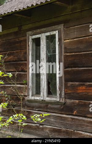 Finestra rotta di una vecchia casa in legno abbandonata in campagna Foto Stock