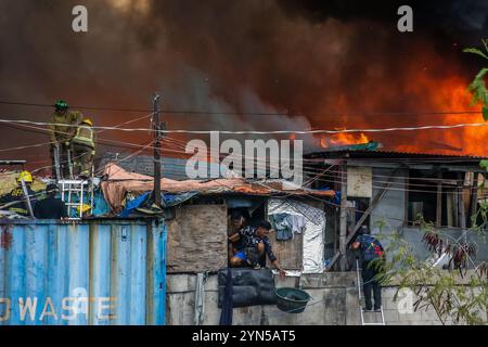 Manila. 24 novembre 2024. I residenti evacuano con i loro effetti personali attraverso la finestra della loro casa come un enorme incendio inghiottisce un'area di slum a Manila, nelle Filippine, il 24 novembre 2024. Almeno 2.000 famiglie sono rimaste senza casa dopo un enorme incendio che ha colpito una comunità residenziale nella capitale filippina domenica, hanno detto le autorità locali. Crediti: Rouelle Umali/Xinhua/Alamy Live News Foto Stock