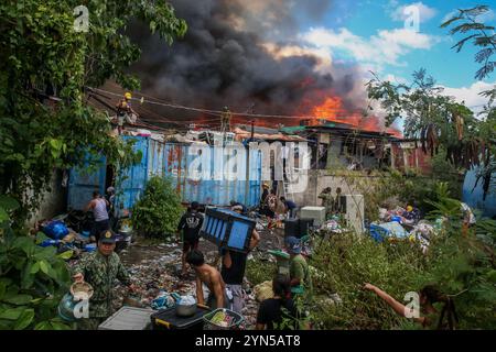 Manila. 24 novembre 2024. I residenti evacuano con i loro effetti personali come un enorme incendio inghiottisce un'area di slum a Manila, nelle Filippine, il 24 novembre 2024. Almeno 2.000 famiglie sono rimaste senza casa dopo un enorme incendio che ha colpito una comunità residenziale nella capitale filippina domenica, hanno detto le autorità locali. Crediti: Rouelle Umali/Xinhua/Alamy Live News Foto Stock