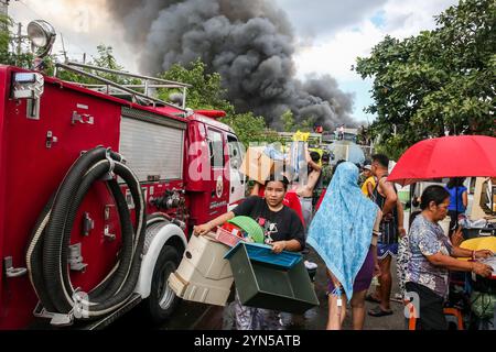 Manila. 24 novembre 2024. I residenti evacuano con i loro effetti personali come un enorme incendio inghiottisce un'area di slum a Manila, nelle Filippine, il 24 novembre 2024. Almeno 2.000 famiglie sono rimaste senza casa dopo un enorme incendio che ha colpito una comunità residenziale nella capitale filippina domenica, hanno detto le autorità locali. Crediti: Rouelle Umali/Xinhua/Alamy Live News Foto Stock