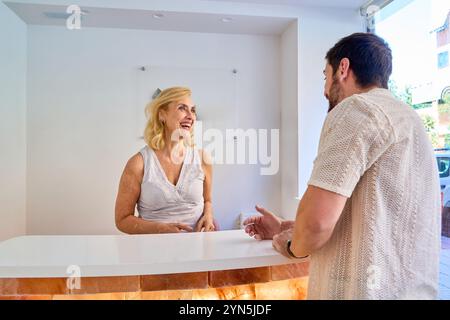 Una donna e un uomo sono davanti a un bancone. La donna sorride e l'uomo la sta guardando Foto Stock