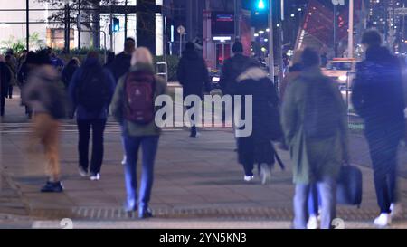 Varsavia, Polonia. 21 novembre 2024. Fotografia di strada di persone per strada di notte. Il profilo pedonale si presenta sullo sfondo di un edificio moderno. Foto Stock