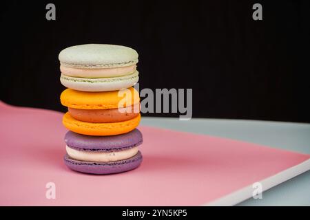 Una collezione di macaron colorati disposti su uno sfondo rosa tenue. La foto evidenzia la natura delicata e artistica di questo classico pas francese Foto Stock